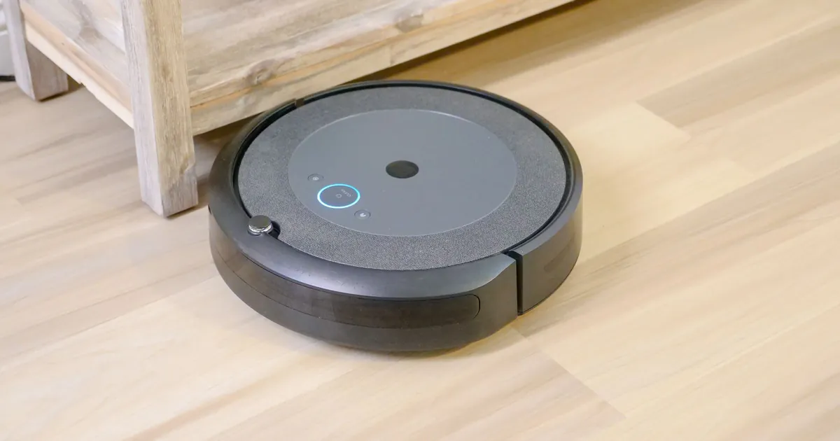Robot aspirapolvere su un parquet chiaro accanto a una mensola in legno