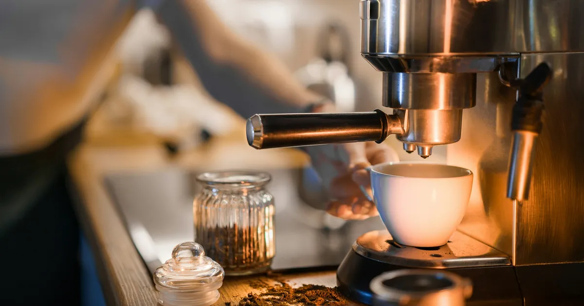 Macchina da caffè espresso in acciaio che eroga il caffè in una tazzina bianca