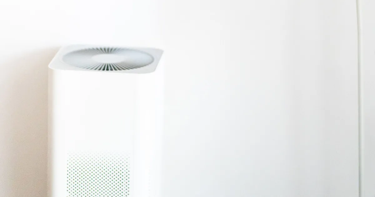 Purificatore d'aria bianco accanto a una lampada da terra in una stanza luminosa